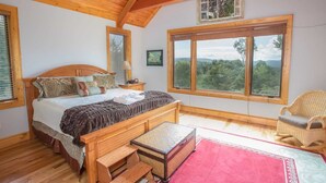 Une chambre à coucher avec un lit en bois, une grande fenêtre et une vue sur l’extérieur.