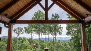 Une terrasse en bois offrant une vue sur une forêt et des montagnes.