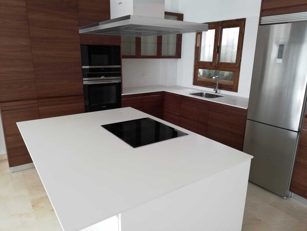Uma cozinha moderna com ilha central, eletrodomésticos de aço inoxidável e armários de madeira.