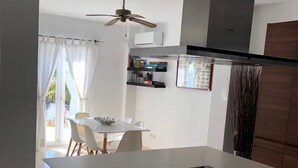 A modern kitchen with a central island, white cabinetry, and a ceiling fan. - Villa with a stunning sea view, located by the poolside and close to the beach (La Herradura)