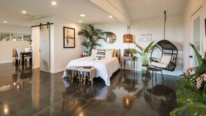 Un dormitorio amplio con una cama grande, una silla colgante y una planta en maceta.