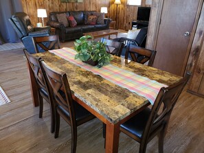A dining area with a wooden table, chairs, and a colorful table runner.