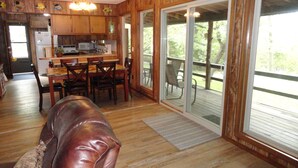 A wooden interior with a dining area, kitchen, and sliding glass doors leading to a deck.