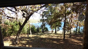 A view from inside a cabin or lodge looking out to a lake with trees and a wooden deck.