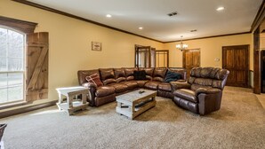Ein geräumiges Wohnzimmer mit einer großen, L-förmigen Couch, einem Holztisch und einem Kamin.