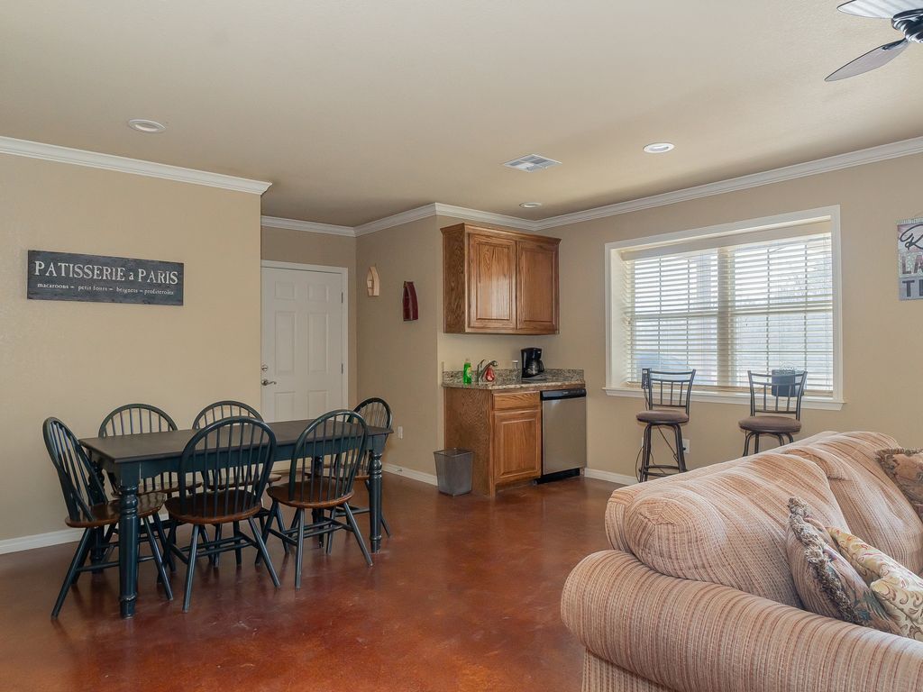 A dining area with a table and chairs, a kitchen with a dishwasher, and a window with blinds.