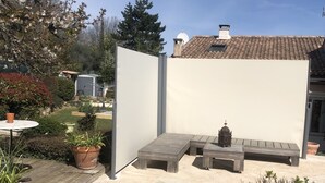 A backyard with a pool, wooden deck, potted plants, and a white wall. - Mimet <season 1/5 to 30/9 >week 630€ or 90€/nuit (Mimet)