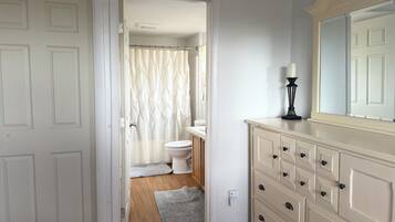 Een badkamer met toilet, douchegordijn en een wastafel met spiegel en lamp.