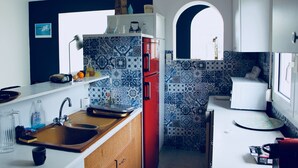 Una cocina compacta con un lavamanos, un refrigerador rojo y un microondas.