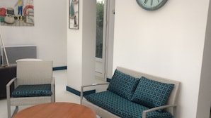 Una habitación con un sofá, una mesa redonda y un reloj de pared.