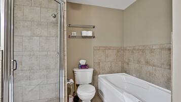 Une salle de bain avec douche, toilettes et baignoire.