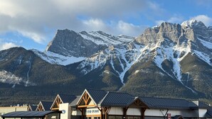 A mountain lodge with a view of snow-capped peaks. - Inviting Condo – Hot Tub & Relaxing Atmosphere! (Canmore)