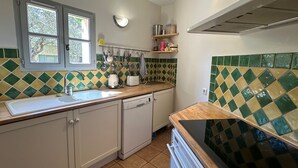 Cozinha compacta com pia, lava-louças e fogão. Utensílios pendurados e janela sobre a pia.