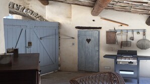 Uma cozinha rústica com uma porta azul, um recorte em formato de coração e uma churrasqueira.