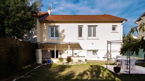 A two-story house with a tiled roof, a covered porch, and a small garden area with a lawn and potted plants. - Apartment 1 * "The House of the Artist" (Coulounieix-Chamiers)