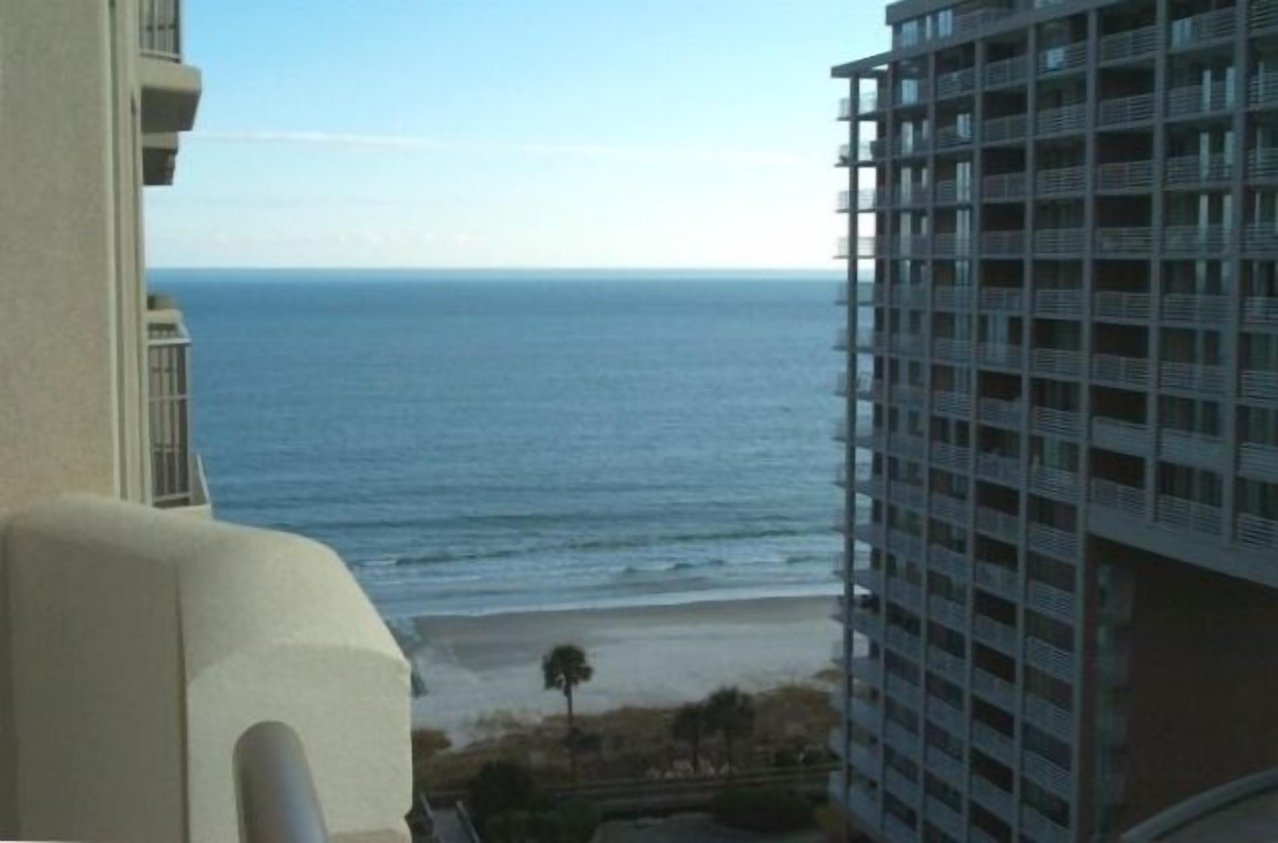 Vista de una playa desde un edificio alto con balcones que dan al océano.