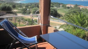 A balcony with a view of the sea and mountains, a chair, and a table. - The most beautiful place in corsica, beaches, garden, terrace, private parking (Lumio)