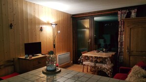 A cozy room with wooden walls, a television, a table with a tablecloth, and a chair. - Studio Vallouise, Puy saint vincent, Pelvoux, Les Écrins. Magnificent view (vallouise)
