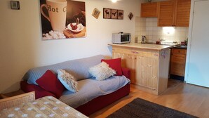 A compact living space with a kitchenette, a sofa with patterned cushions, and a coffee table. - Studio Vallouise, Puy saint vincent, Pelvoux, Les Écrins. Magnificent view (vallouise)
