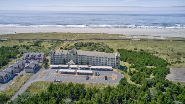 A hotel with a parking lot, a beach, and a forested area. - Beach Please- Oceanfront easy access to the beach (Long Beach)