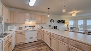 A modern kitchen with wooden cabinets, a microwave, an oven, and a coffee maker. - Beach Please- Oceanfront easy access to the beach (Long Beach)