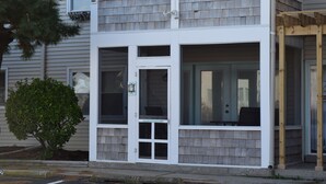 A two-story building with a white exterior, large windows, and a small front porch. - Pet Friendly Ocean Front Building Downtown Dewey Beach Sleeps 7 (Dewey Beach)