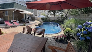 Quintal com piscina, móveis de jardim e área de varanda.