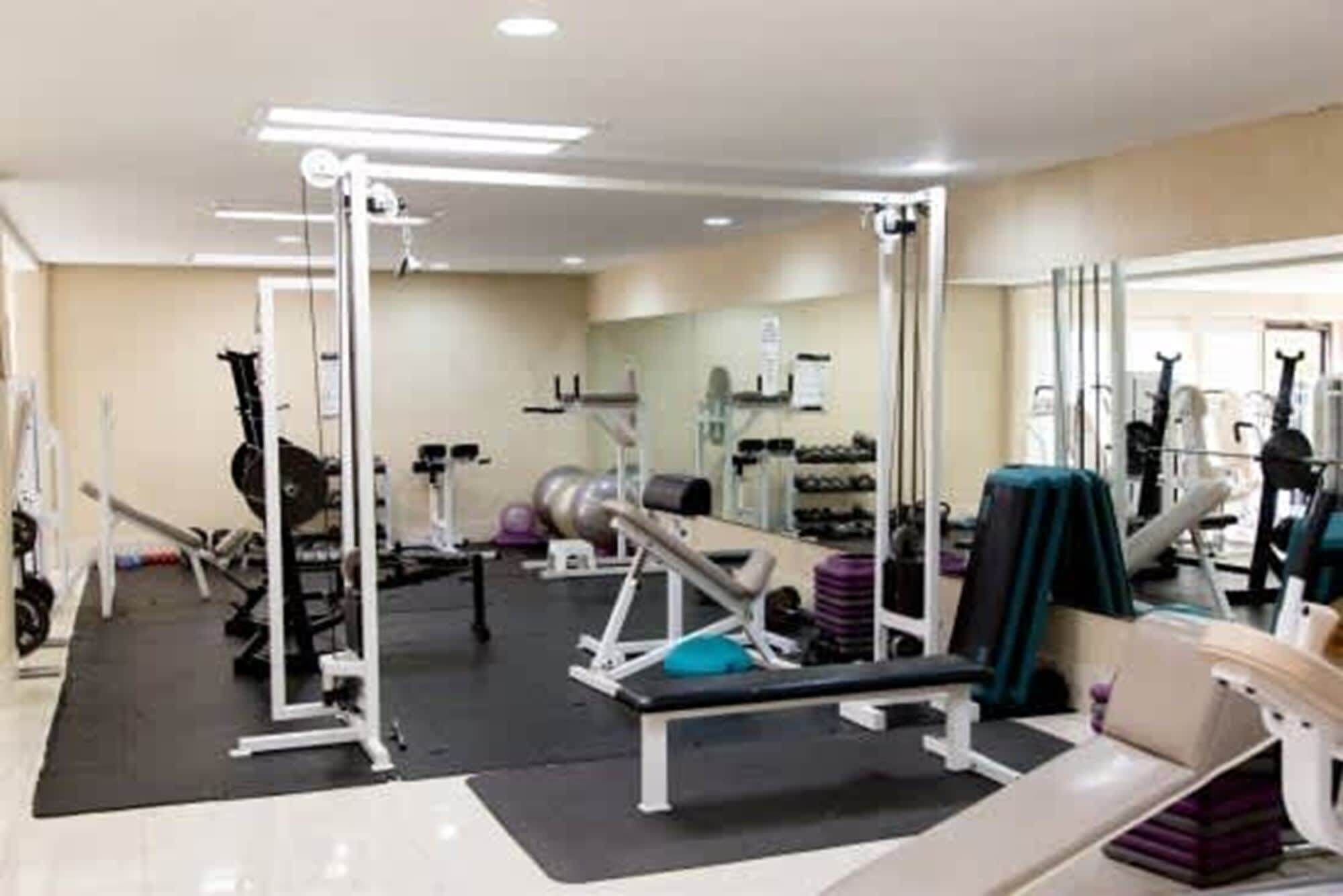 A gym with various exercise equipment, including a bench press, weight machines, and free weights.
