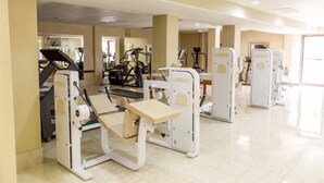 Un gimnasio con máquinas de cardio, zona de pesas y espejo grande.
