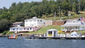 Une propriété située au bord de l’eau, dotée d’un quai, d’un petit bateau et d’un bâtiment sur lequel flotte un drapeau.