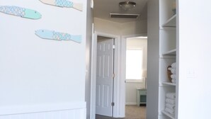 A hallway with a carpeted floor, white walls, and a door leading to another room.