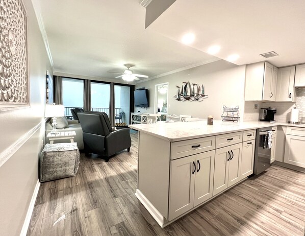 A modern kitchen with a large island, white cabinetry, and a ceiling fan.