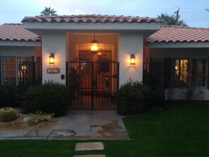 Traditional home with a tiled roof and symmetrical facade, featuring a gated entrance and a well-manicured lawn.