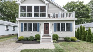 A two-story house with a front porch, a balcony, and a number 63 on the door.