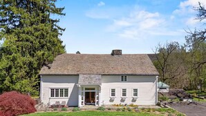 A two-story white house with a front porch, a chimney, and a well-maintained lawn.