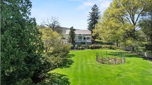 A well-maintained lawn, a garden with flowers, and a house with a porch.
