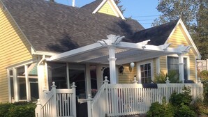 A two-story house with a covered porch and a white fence. - Oceanside Retreat  Hubbards Nova Scotia (Hubbards)
