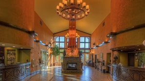 A spacious lobby with a central stone fireplace, large windows, and a chandelier.