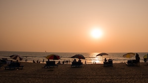 Une plage de sable baignée de soleil, où les gens se détendent à l’ombre de parasols.