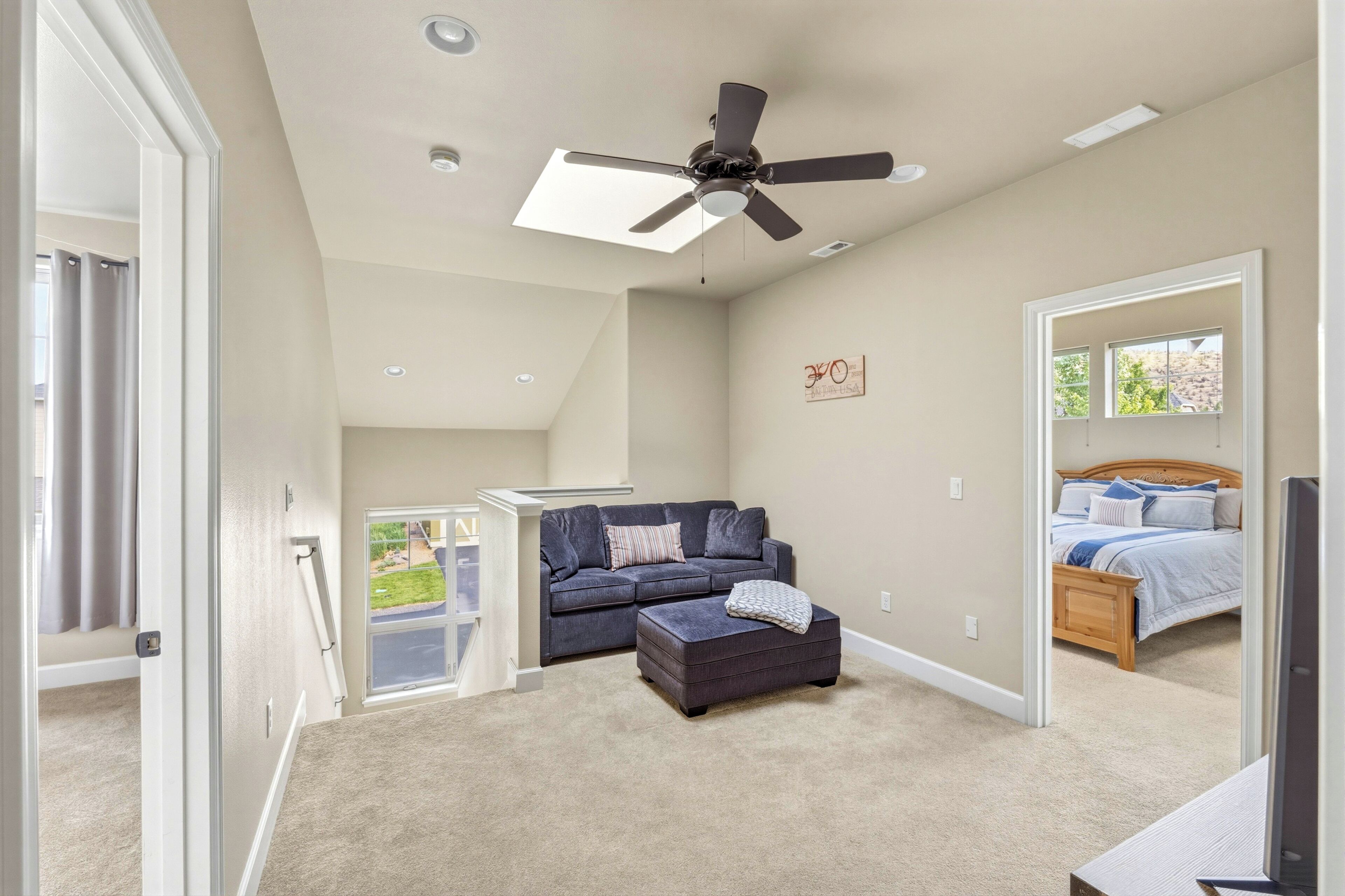 Une chambre à coucher avec un lit, un ventilateur de plafond, une fenêtre et une porte.