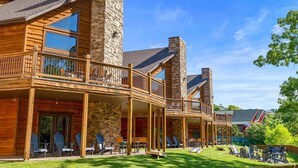 A log cabin with a stone tower, wooden balconies, and outdoor seating. - Gorgeous 10 Bedroom Lakefront Lodge (Branson)