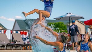 A poolside scene with a person performing a flip into the water, surrounded by onlookers. - Gorgeous 10 Bedroom Lakefront Lodge (Branson)