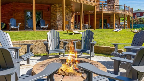 A wooden lodge with a fire pit surrounded by Adirondack chairs. - Gorgeous 10 Bedroom Lakefront Lodge (Branson)