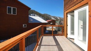Un bâtiment en bois doté d’un balcon, d’une porte avec un panneau de verre et offrant une vue sur une montagne.