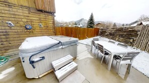 Een jacuzzi en buitentafel met stoelen in een achtertuin.