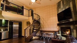 Een ruime woonkamer met een wenteltrap, een open haard en een keuken met moderne apparatuur.