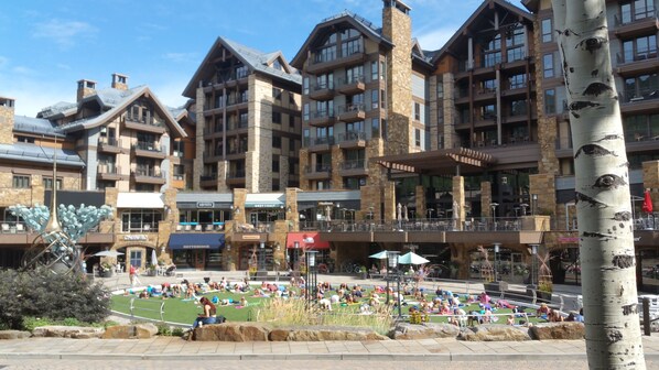 A hotel with multiple floors, stone facade, and outdoor seating areas.