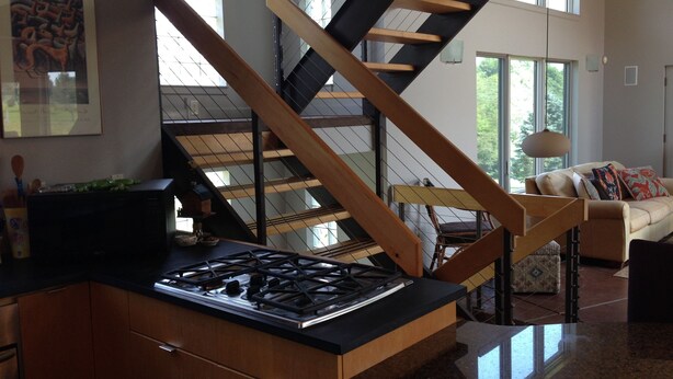 A modern kitchen with a gas stove, wooden cabinets, and a large window overlooking a balcony. - Unique home five minutes from Miami University (Oxford)