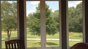A room with three large windows offering a view of a green landscape, a ceiling fan, and two wooden chairs. - Unique home five minutes from Miami University (Oxford)
