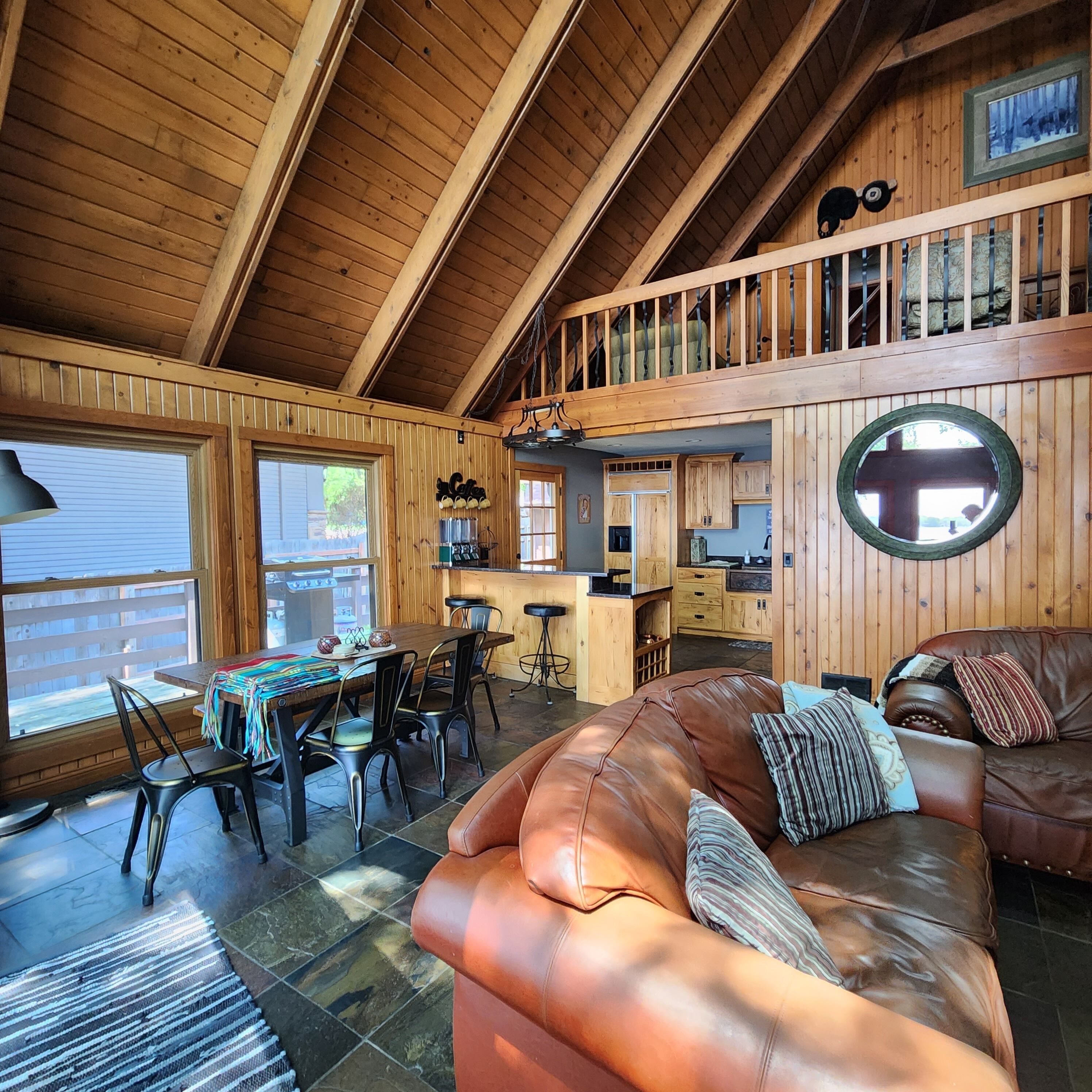 Un intérieur de chalet chaleureux avec un coin repas, un canapé en cuir et une cuisine.
